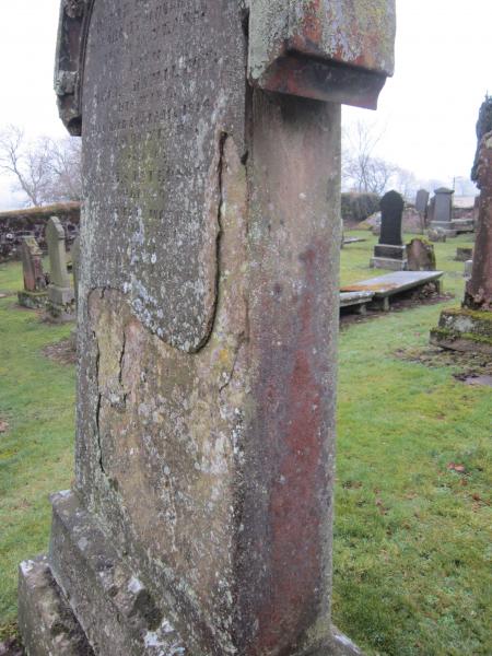 A side on colour photo showing the flaking surface of gravestone and loss of writing and original surface